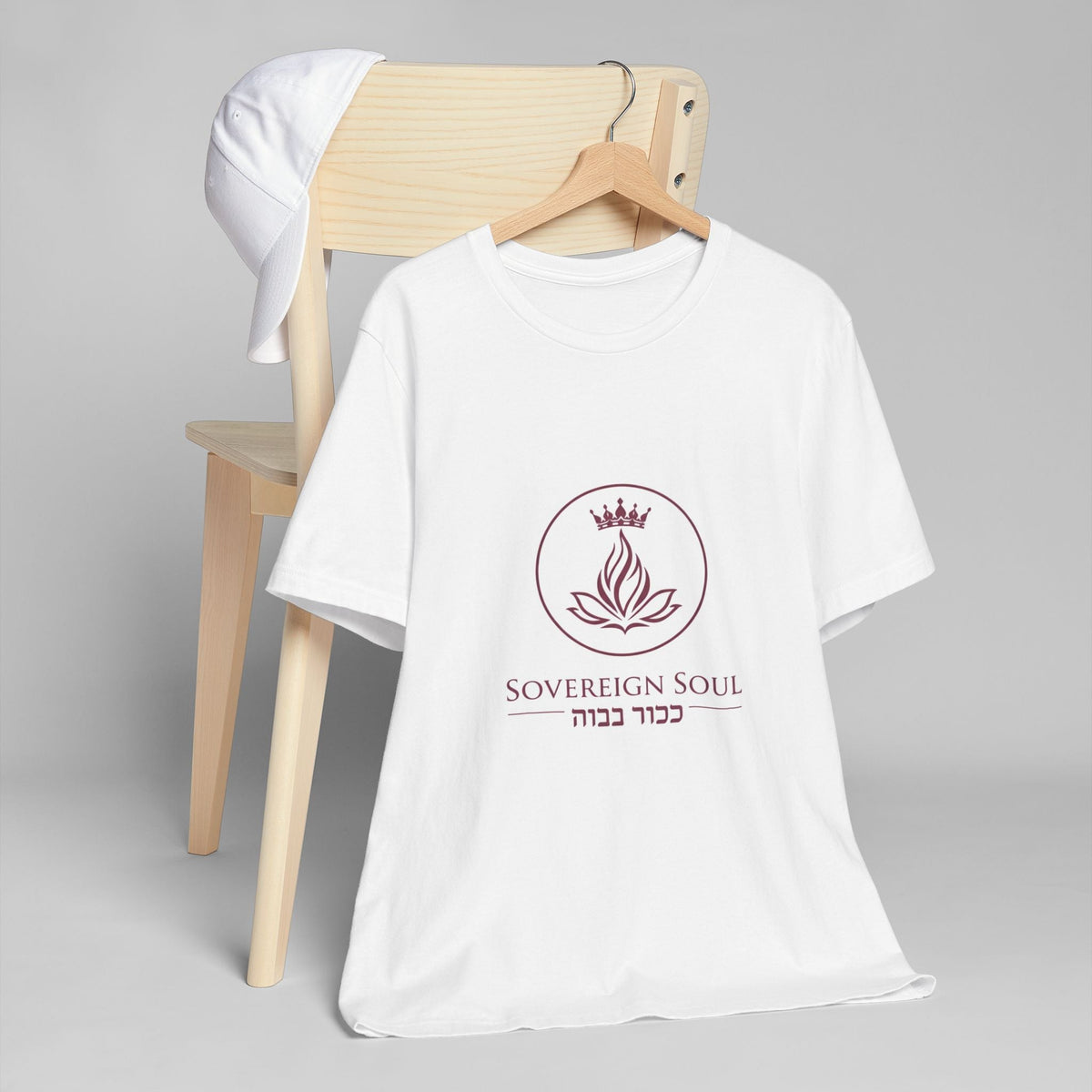Sovereign Soul .Store white cotton t-shirt featuring a crown and flame logo with Hebrew text on a wooden chair.